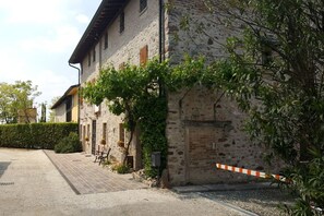 A rustic stone building with a gravel driveway and a gated entrance. - AMAZING HISTORICAL COUNTRY HOUSE (Pozzolengo)