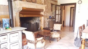 A dining area with a fireplace, stone wall, and a kitchen with vintage cabinets. - AMAZING HISTORICAL COUNTRY HOUSE (Pozzolengo)