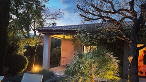 Un patio esterno moderno con poltrone lounge, una pergola e un vialetto in pietra.