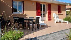 Ein Haus mit Terrasse, Tisch und Stühlen sowie einem Poolbereich.