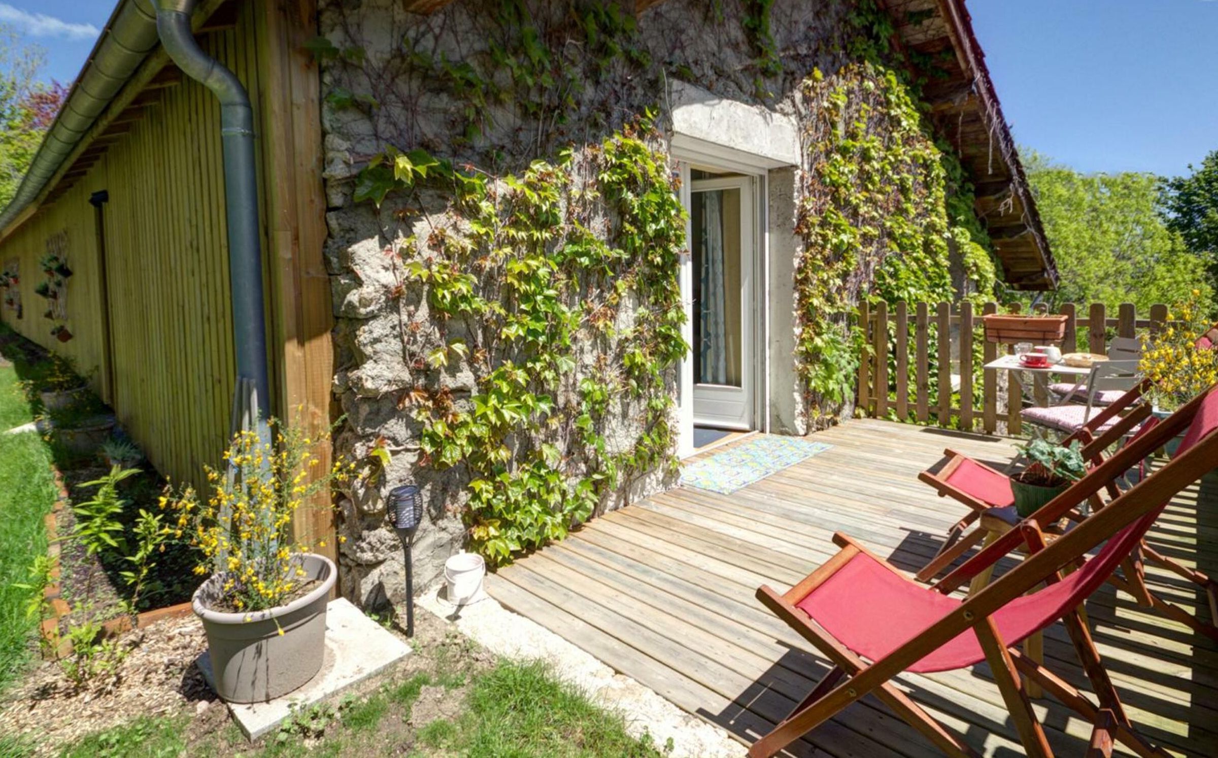 A rustic stone building with a wooden deck and outdoor seating.
