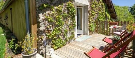 A rustic stone building with a wooden deck and outdoor seating.