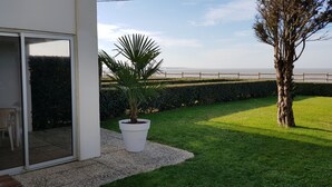 Un patio con planta en maceta, un árbol y vista al mar.