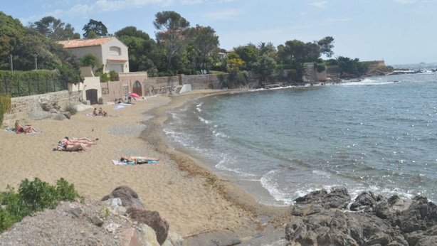 A beach with a stone wall, a building with a tiled roof, and a clear sky. - 2-room apartment near beach with garden in Saint Aygulf (Saint-Aygulf)