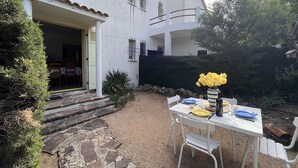 A white house with a stone pathway leading to a patio table set with plates, a vase of yellow flowers, and a bottle. - 2-room apartment near beach with garden in Saint Aygulf (Saint-Aygulf)