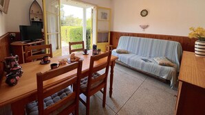 A cozy room with a dining table, chairs, a sofa, and a television. - 2-room apartment near beach with garden in Saint Aygulf (Saint-Aygulf)