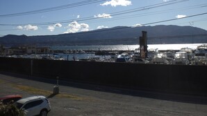 A marina with boats docked, a mountain in the background, and power lines overhead. - Marina bay Numazu (Numazu)