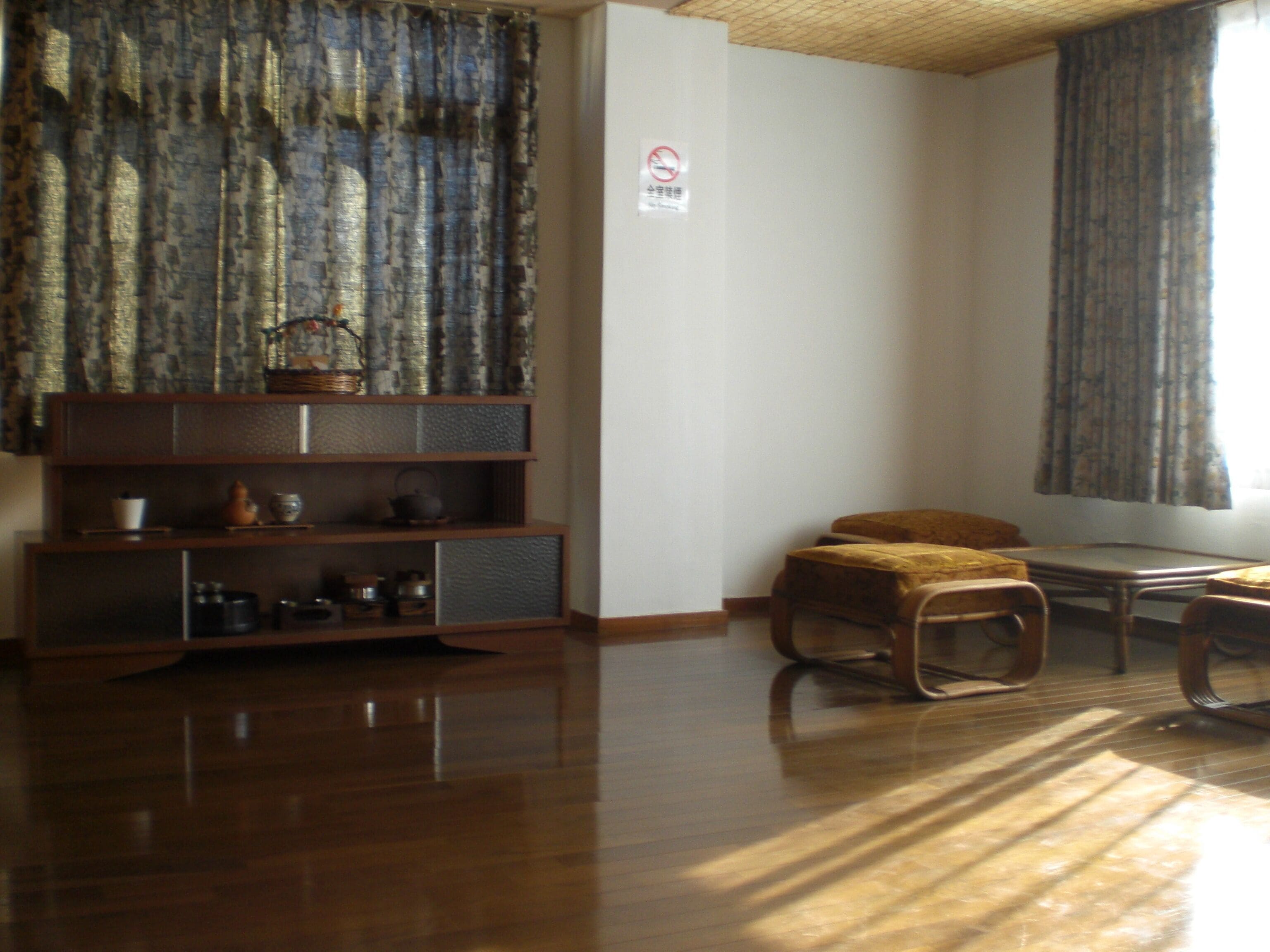 A room with a wooden floor, a bookshelf, a chair, and a table.