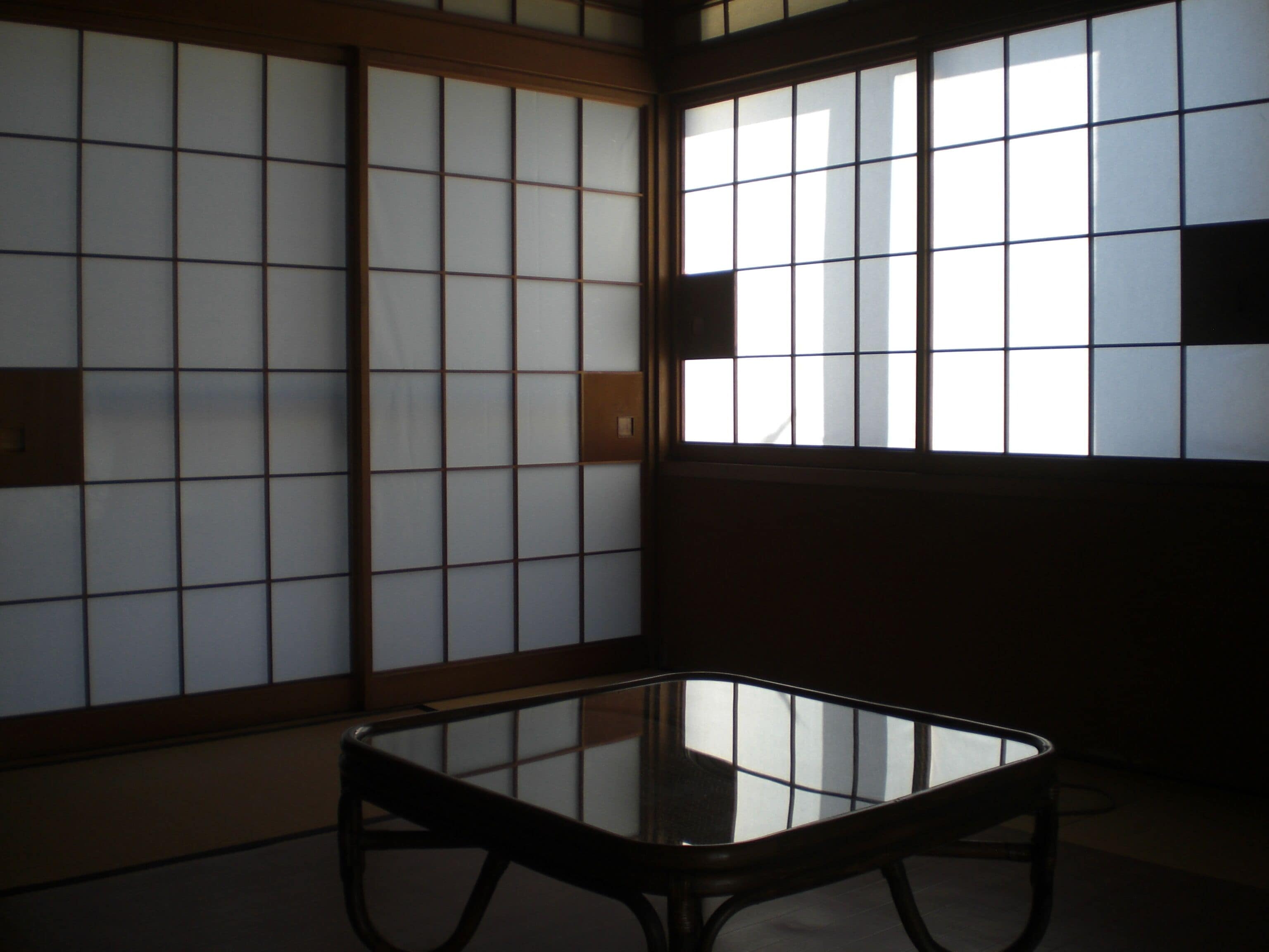A traditional Japanese room with sliding shoji screens, a tatami mat floor, and a low wooden table.