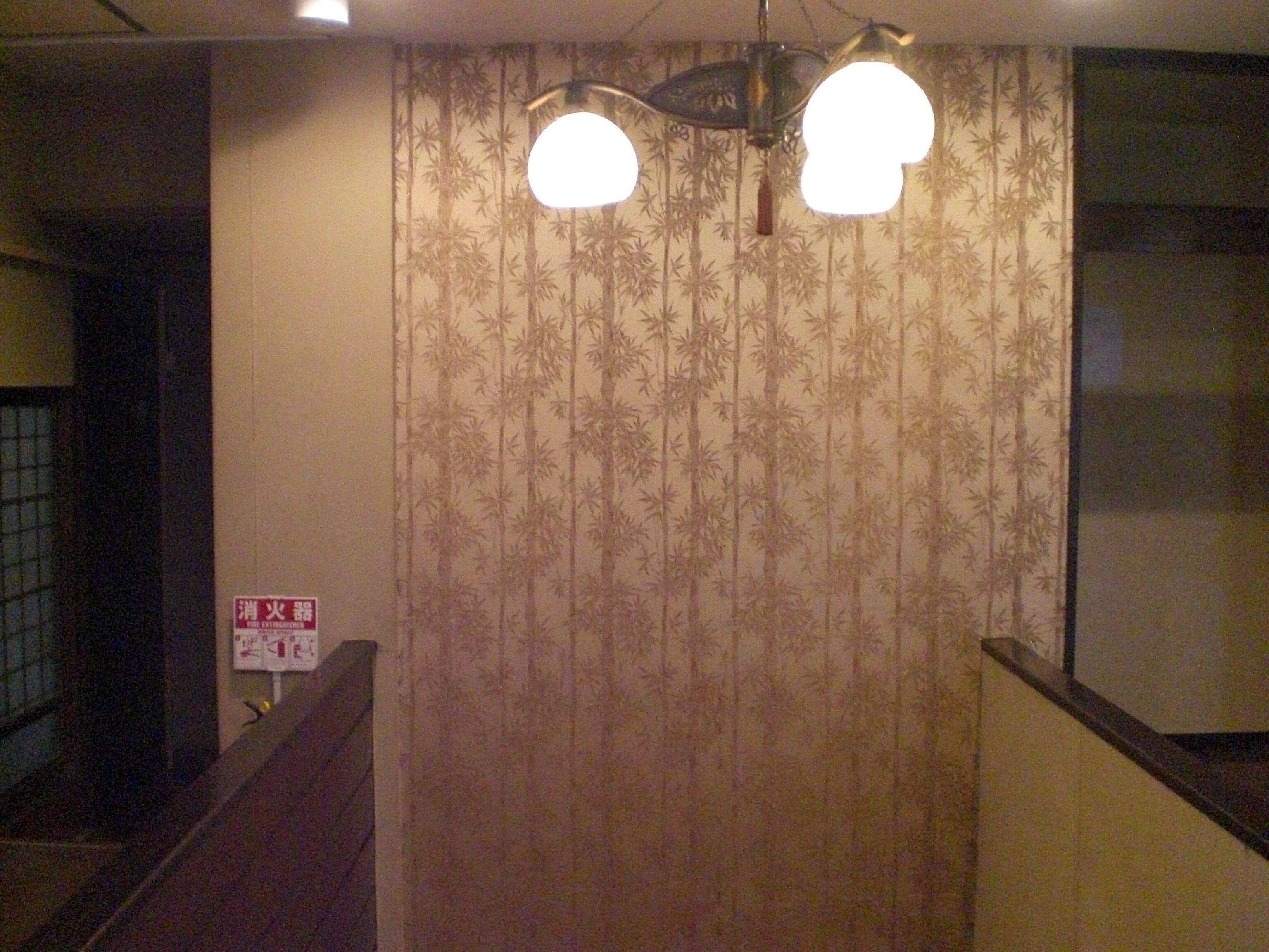 Een trap met een wand met bamboetextuur en een bordje met daarop een vluchtroute.