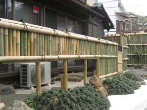 A traditional Japanese building with a bamboo fence, a stone lantern, and a small garden with rocks and plants. - Marina bay Numazu (Numazu)