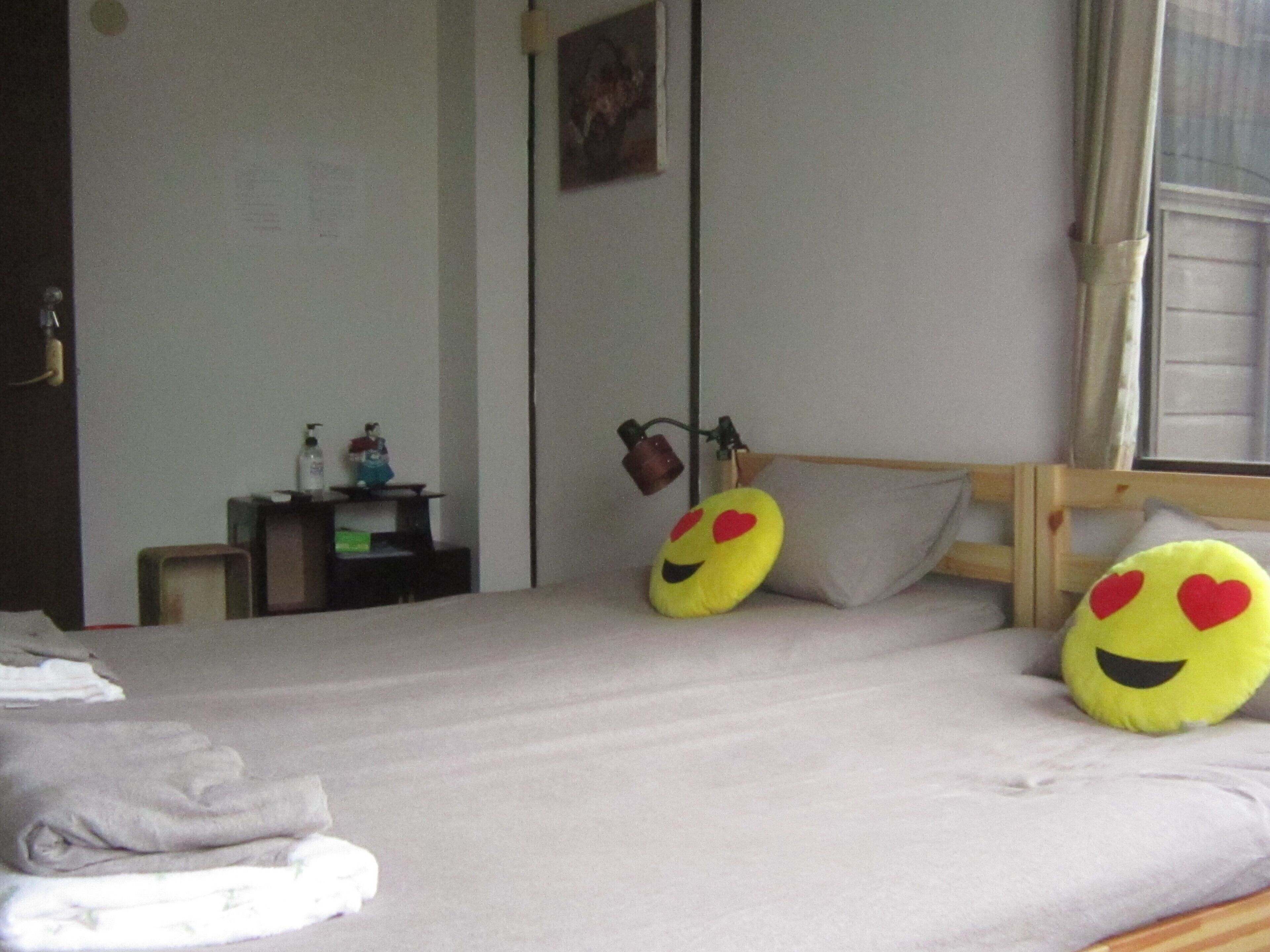 A bedroom with a bed, pillows, a bedside table, and a window.