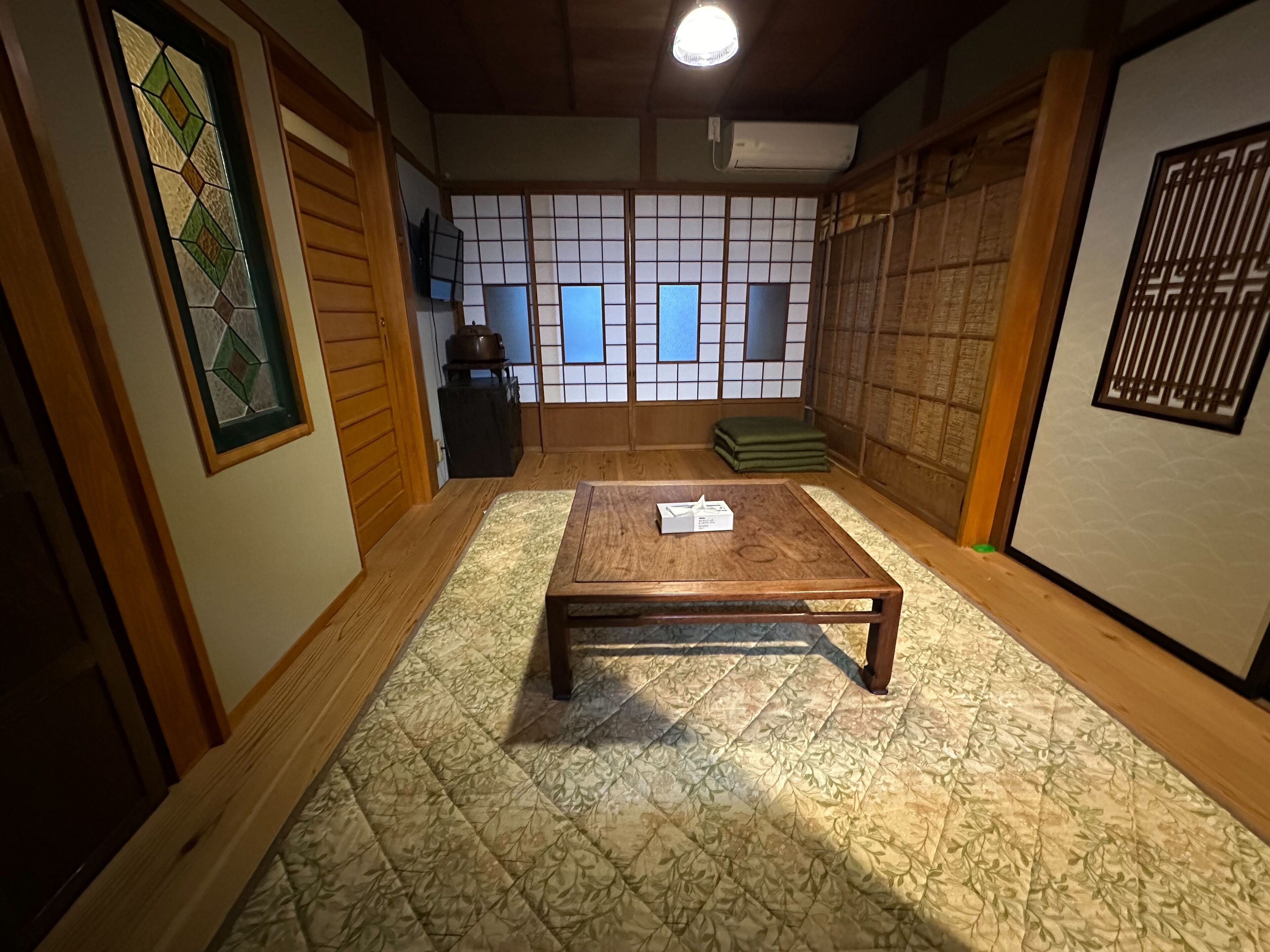 Una habitación japonesa tradicional con suelo de tatami, una mesa de madera baja y puertas correderas shoji.