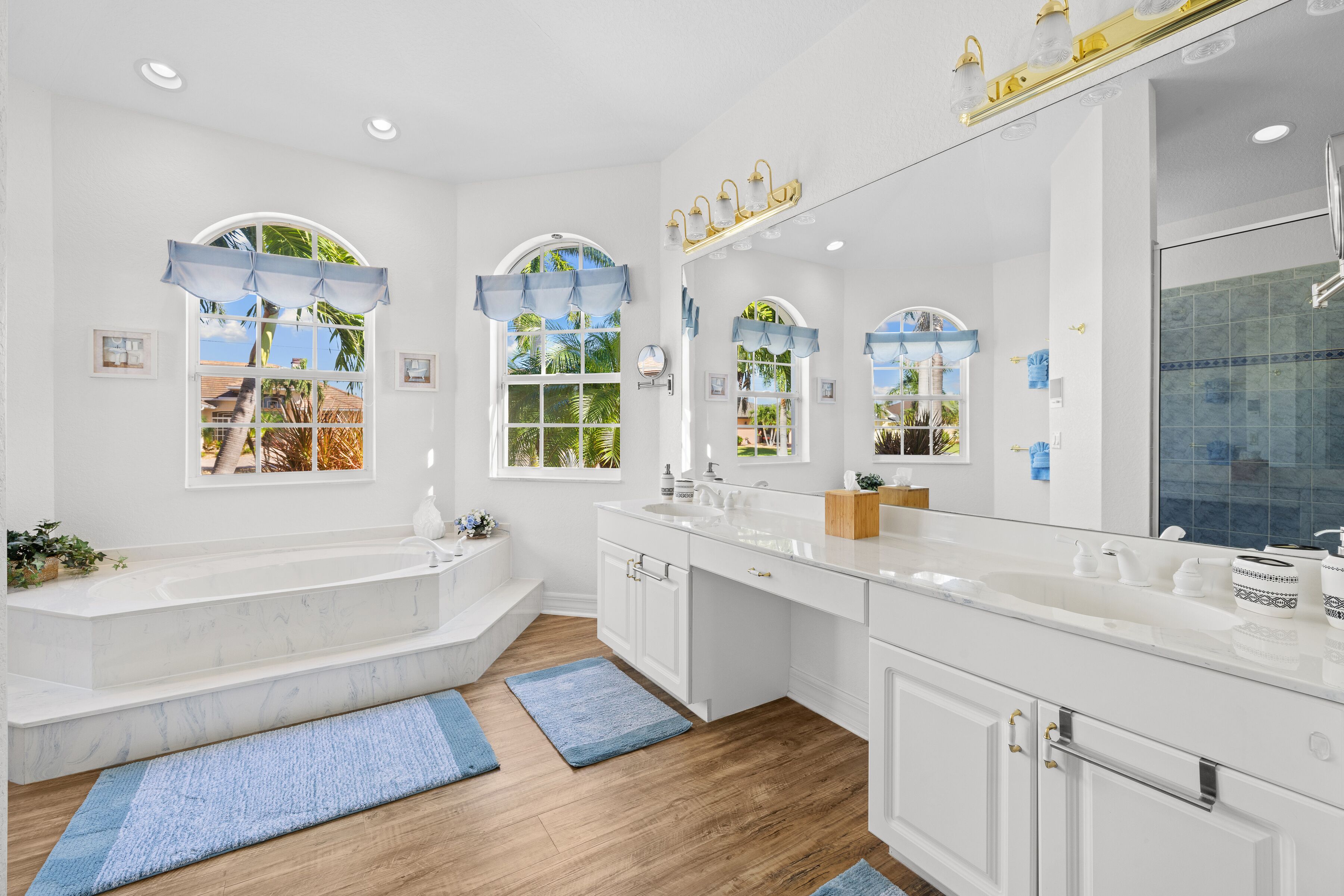 A modern bathroom with a bathtub, double sinks, and a large mirror.
