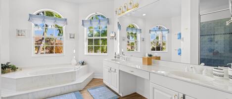 A modern bathroom with a bathtub, double sinks, and a large mirror.
