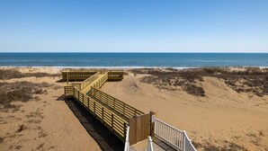 Eine Holzpromenade führt zu einem Strand mit freiem Blick auf das Meer.