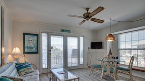 A living room with a sofa, coffee table, and chairs, a ceiling fan, and a dining area with a table and chairs. - Summer Breeze 312 1 Bedroom Condo by RedAwning (Miramar Beach)