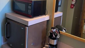 Angolo cottura con forno a microonde, macchina del caffè e un piccolo armadietto.