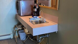 Un bagno compatto con lavandino, specchio e macchina del caffè.