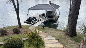 A stone pathway leading to a dock with a covered seating area by the water.