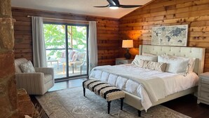 A bedroom with a large bed, a bench, a nightstand, a lamp, and a world map on the wall.