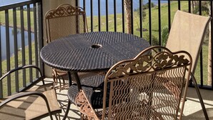 Ein Balkon mit rundem Tisch und Stühlen, mit Blick auf einen See und einen Golfplatz.