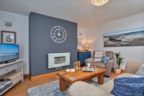 Relax in this stylish living room with a flat-screen TV, comfortable sofa, and a wooden coffee table.