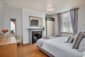 Enjoy a cozy stay in this stylish room featuring a large bed, fireplace, and wardrobe.