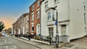A row of terraced houses with a clear road in front, a blue sign indicating a one-way street, and a black metal fence along the sidewalk. - Oystercatcher (Whitby)