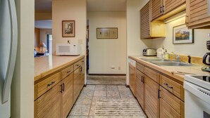 Una cocina con armarios de madera, microondas, tostadora y pileta.
