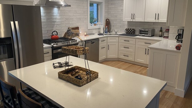 A modern kitchen with white cabinetry, stainless steel appliances, and a central island. - Brand New Charming Beach House (Mattituck)