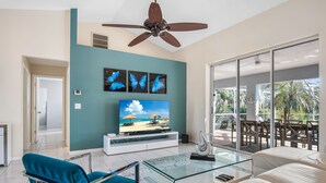 A modern living room with a TV, blue and white furniture, a ceiling fan, and a view of the outdoors. - /\ Amazing Location/\ 10 mins away from beach and Mercato/ New Diamond in Naples (Naples)