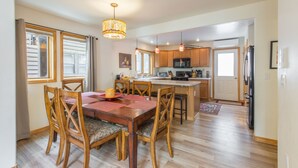 Una cocina amplia con armarios de madera, una isla central y un comedor con mesa y sillas de madera.