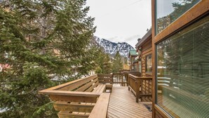 Una terraza de madera con bancos, con vistas a un bosque y montañas.