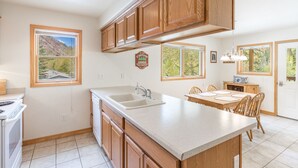 Une cuisine moderne avec des meubles en bois, un grand îlot central et un coin repas comprenant une table et des chaises.