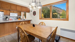 Une cuisine avec des meubles en bois, un micro-ondes blanc et un coin repas comprenant une table et des chaises en bois.