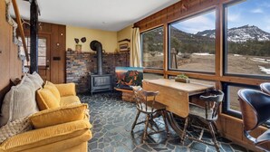 A cozy room with a stone floor, a wooden desk, a chair, a sofa, and a fireplace. - Rustic Cabin | Great Views | Close to Downtown Ouray | STR2025-067 (Ridgway)