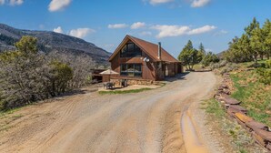 A rustic cabin with a stone foundation, large windows, and a chimney. - Rustic Cabin | Great Views | Close to Downtown Ouray | STR2025-067 (Ridgway)