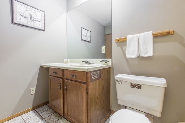 A bathroom with a wooden cabinet, a sink, and a toilet.