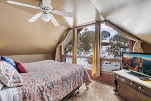 Ein Schlafzimmer mit Bett, Deckenventilator, Fernseher und Fenster mit Schnee