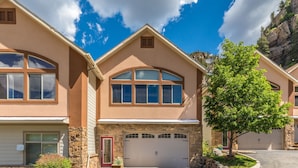 A two-story house with a stone facade, a garage, and a driveway. - Unbeatable Location | Across from Ouray Hot Springs | Walk to Downtown (Ouray)