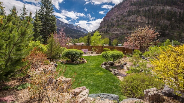 A mountainous landscape with a well-maintained garden, a wooden fence, and a clear sky. - Unbeatable Location | Across from Ouray Hot Springs | Walk to Downtown (Ouray)