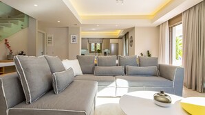 Een moderne woonkamer met een hoekbank, een salontafel en een trap.
