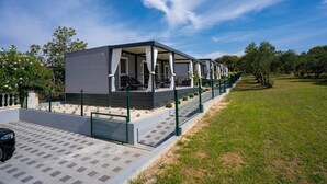 Ein modernes, zweistöckiges Gebäude mit überdachter Außenbestuhlung und einem eingezäunten Garten.