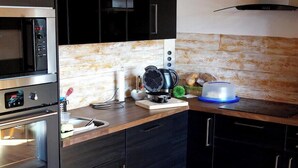 Eine moderne Küche mit dunklen Schränken, einem Edelstahlbackofen, einer Mikrowelle und einer Kaffeemaschine.