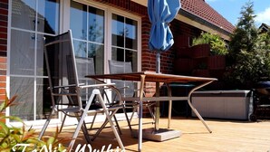 Eine Terrasse im Freien mit Tisch, Stühlen, einem blauen Sonnenschirm und einem Whirlpool.
