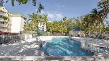 A swimming pool with a 4ft 9in depth, surrounded by lounge chairs and palm trees.