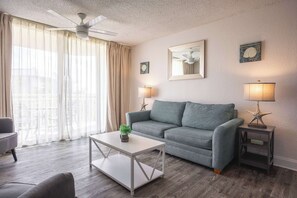 A modern living room with a grey sofa, a white coffee table, and a small side table with a lamp.