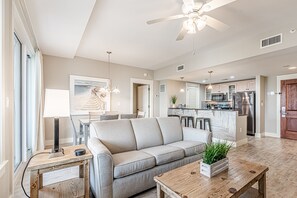 A modern living room with a sofa, coffee table, and a dining area with chairs.