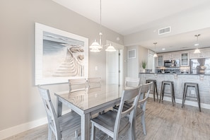 A modern kitchen with a central island, pendant lighting, and a large framed artwork on the wall.